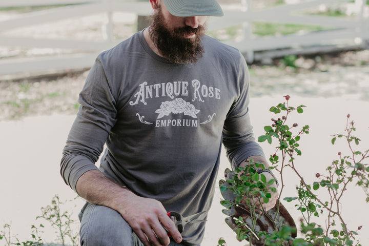man in garden wearing gray long sleeve logo shirt