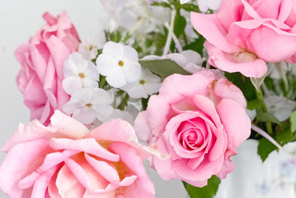 Pink roses and white flowers arranged with greenery.
